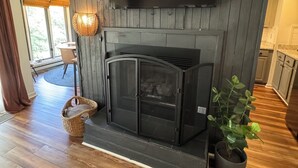Ein modernes Wohnzimmer mit Kamin, einem flachbildfernseher darüber und einem Topfpflanzen.