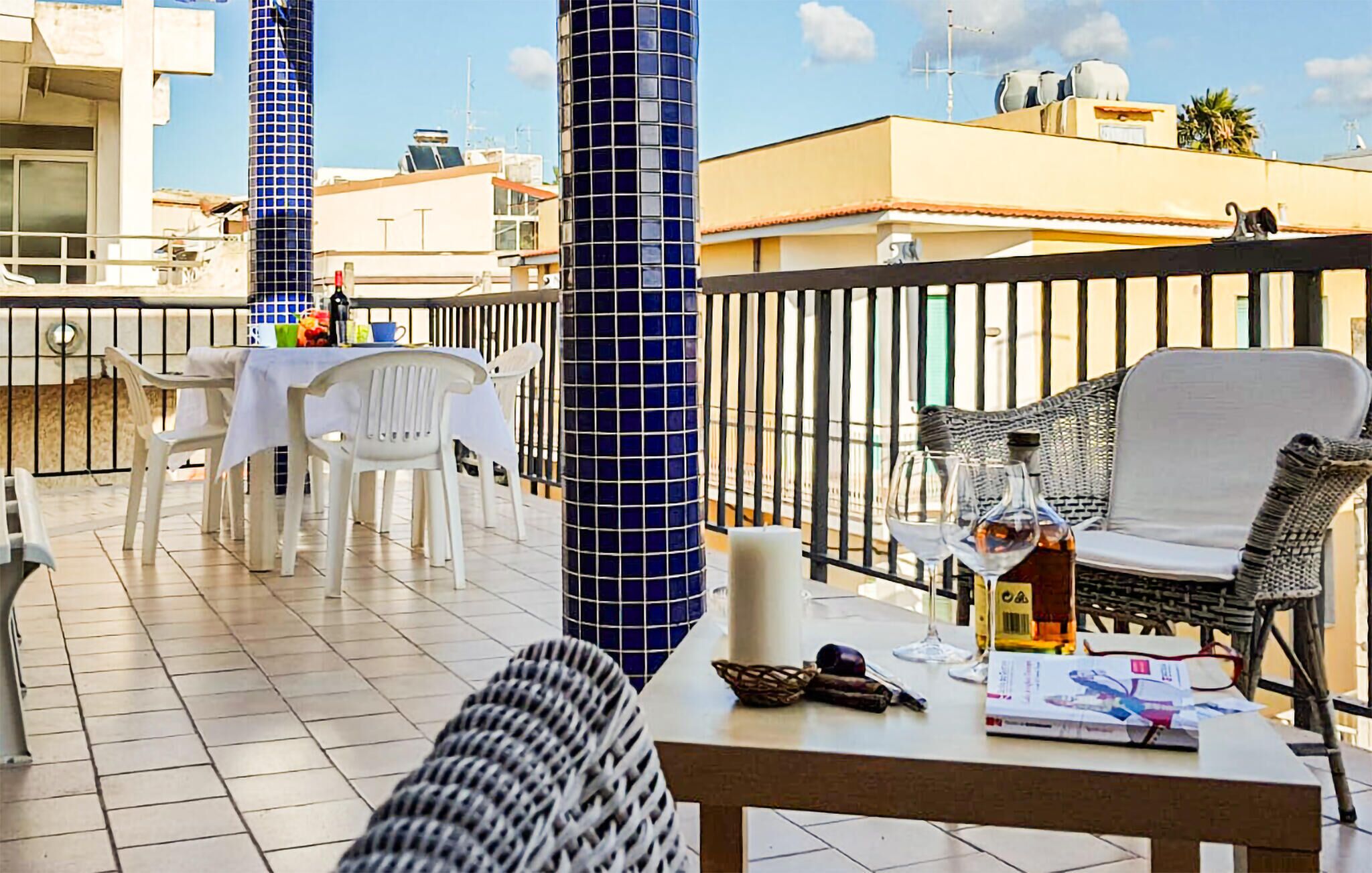 Un balcon avec une table et des chaises, un canapé en osier et une rambarde.