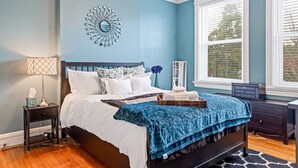 Un dormitorio con cama, mesita de noche, cómoda, espejo y ventana con persianas.