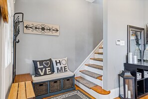A staircase with a bench, a wall-mounted decorative piece, and a mirror with vases.