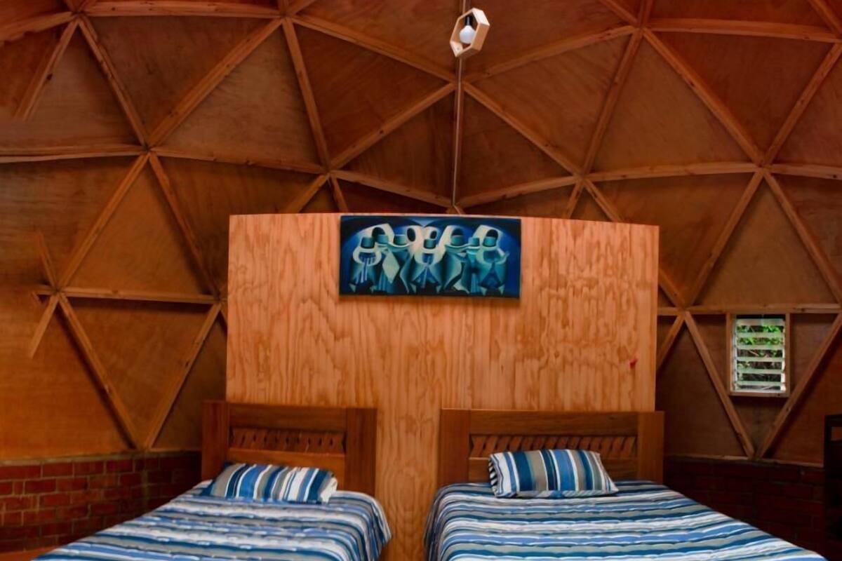A cozy, triangular-roofed room with two beds, a wooden headboard, and a skylight.