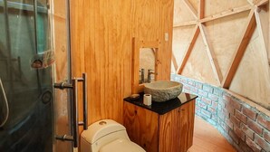 Ein modernes Badezimmer mit Waschtisch aus Holz, einem Steintonne und einer Duschkabine aus Glas.