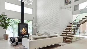 A modern living room with a fireplace, white sofa, and a staircase.