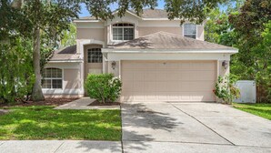 A two-story house with a garage, a driveway, and a well-maintained lawn.