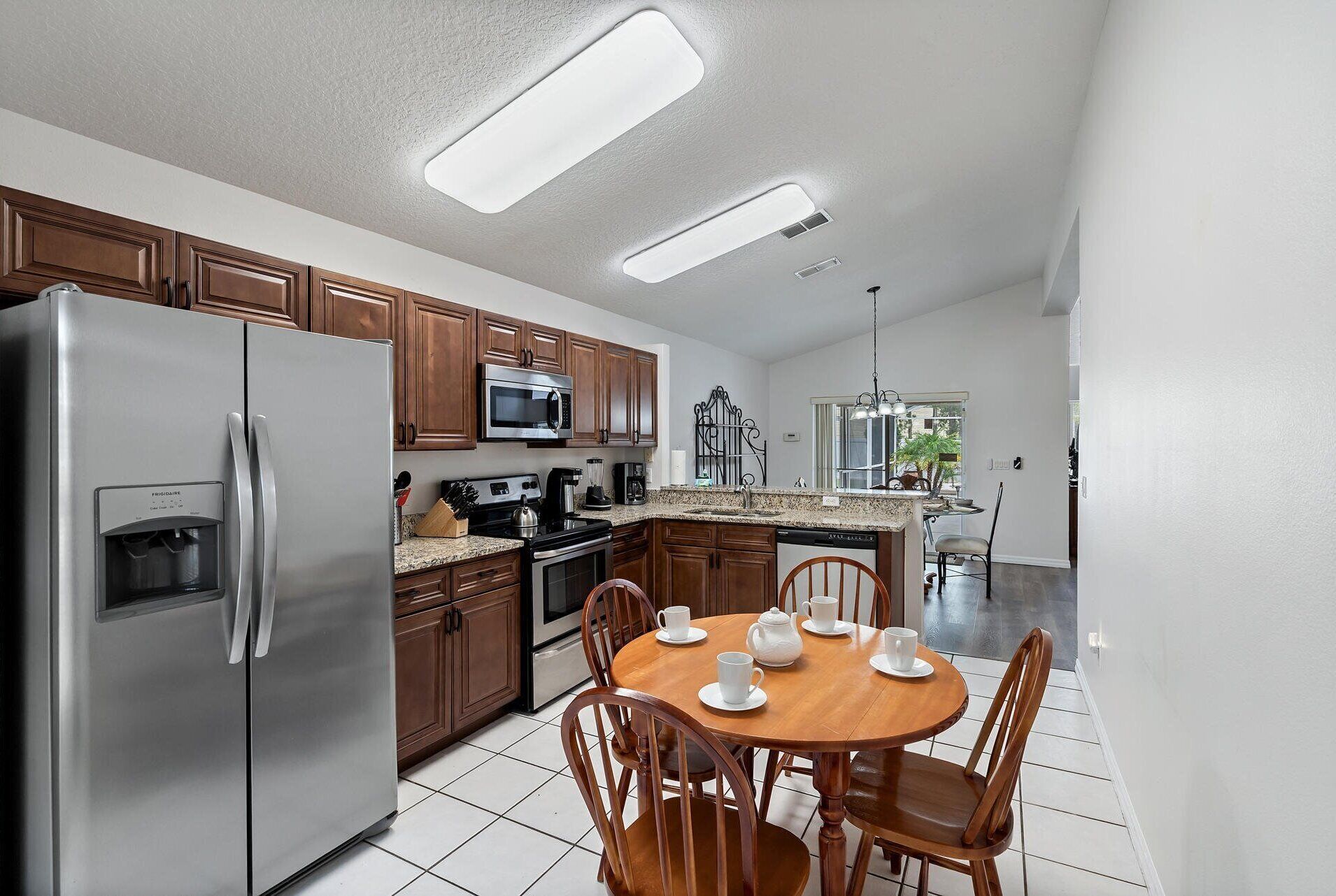 A modern kitchen with stainless steel appliances, wooden cabinets, and a dining area with a round table and chairs.