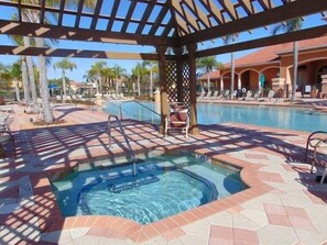 Un área de hidromasaje con piscina, sillas de descanso y una pérgola.