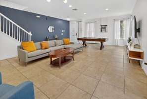 Ein Wohnzimmer mit einer Couch, einem Couchtisch und einem Billardtisch.