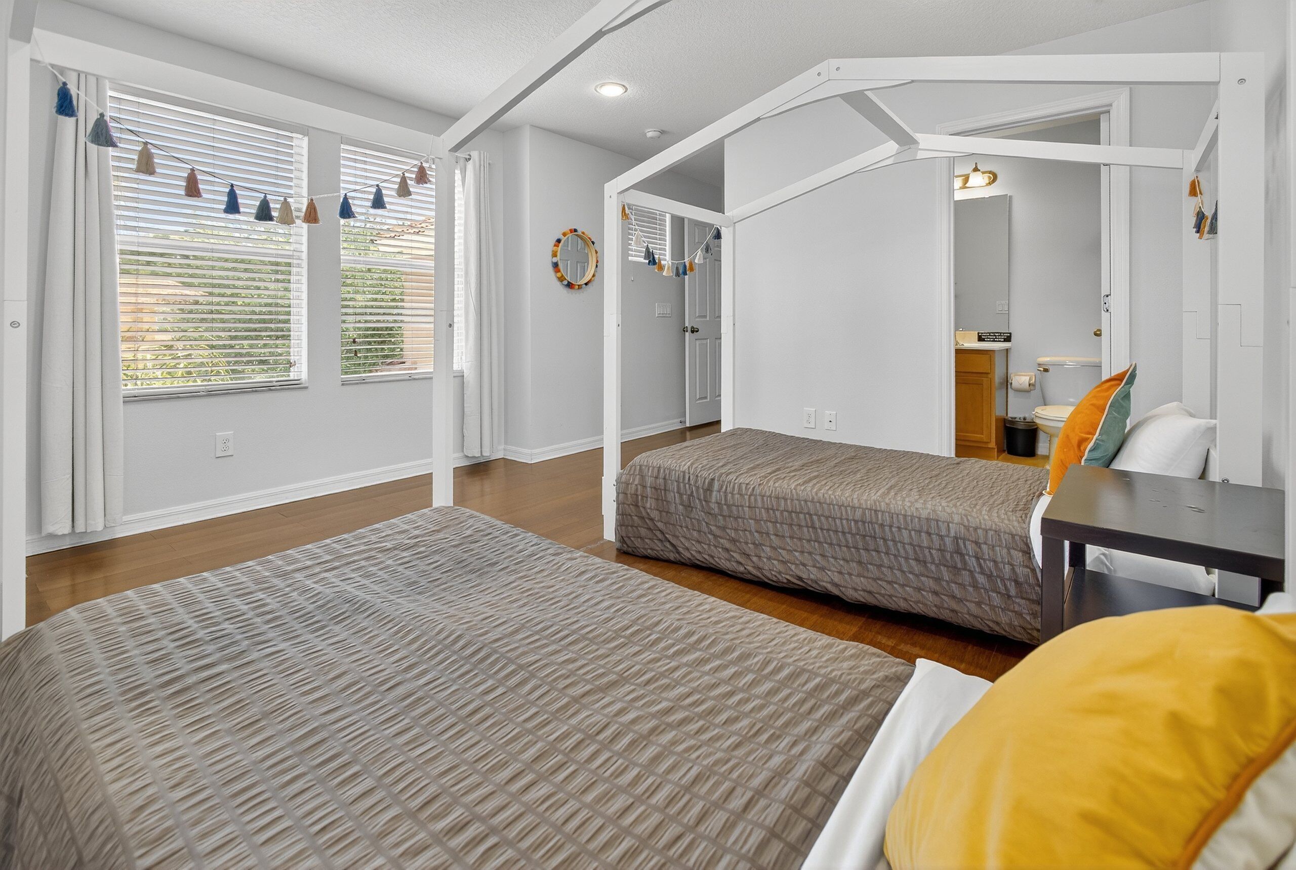 Une chambre avec deux lits, un bureau et une salle de bain visible à travers une porte ouverte.