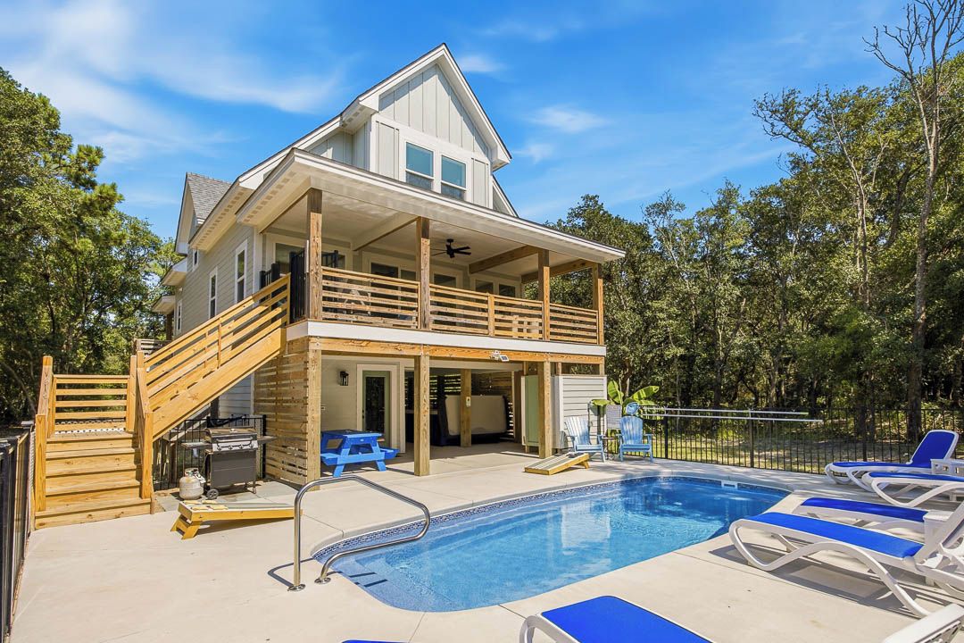 Une maison à deux étages dotée d’un balcon, d’une piscine et de mobilier d’extérieur.
