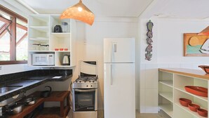 Una cucina moderna con mobili bianchi, piano cottura a gas, microonde e frigorifero.