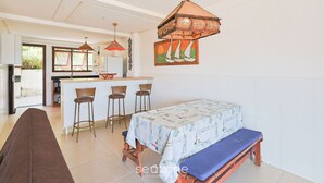 Una cucina moderna con isola centrale, zona pranzo con una panca e sedie, e lampadario a sospensione.