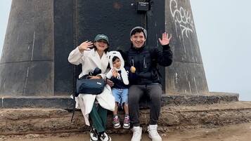 A family posing in front of a large, dark concrete structure with a door, sitting on a dirt ground.