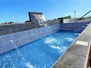 A swimming pool with a blue mosaic tile border and a water feature. - Miel de Luna (Cerro Azul)