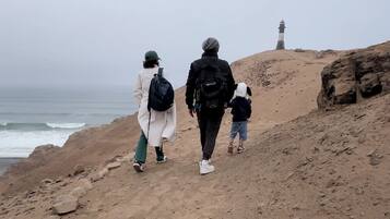 Una playa arenosa con un faro a lo lejos.