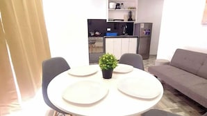 A modern living room with a round dining table, grey chairs, a grey sofa, and a small potted plant. - Miel de Luna (Cerro Azul)
