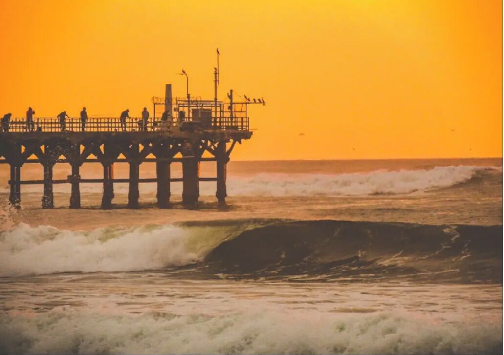 Un muelle que se adentra en el océano, con olas rompiendo contra él.