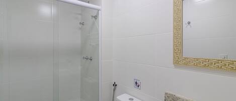 A bathroom with a glass shower enclosure, a toilet, and a sink with a marble countertop.