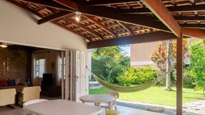 A covered patio with a table and chairs, a hammock, and a view of a garden. - House With Barbecue 350m From the Beach Rul0035 (Ubatuba)