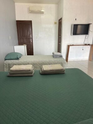 A room with a bed, a desk, a chair, an air conditioning unit, and a television. - Hotel Torre Forte  (Careiro)