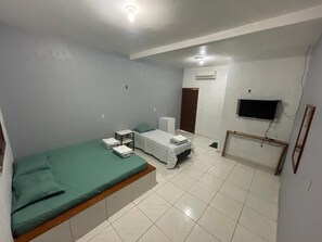 Ein Schlafzimmer mit einem Bett, einem Nachttisch und einem an der Wand montierten Fernseher.