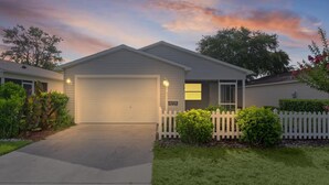 A single-story house with a garage, a covered porch, and a white picket fence. - BETTER THAN A 5 STAR HOTEL WITH GOLF CART WHOLE HOUSE TOTALLY REMODELED (The Villages)