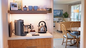 Una cocina compacta con cafetera, hervidor y juego de té sobre la encimera.