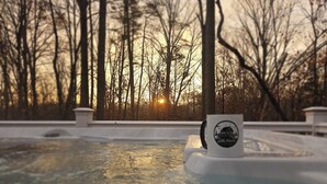 A hot tub with a logo, surrounded by trees and a sunset in the background.