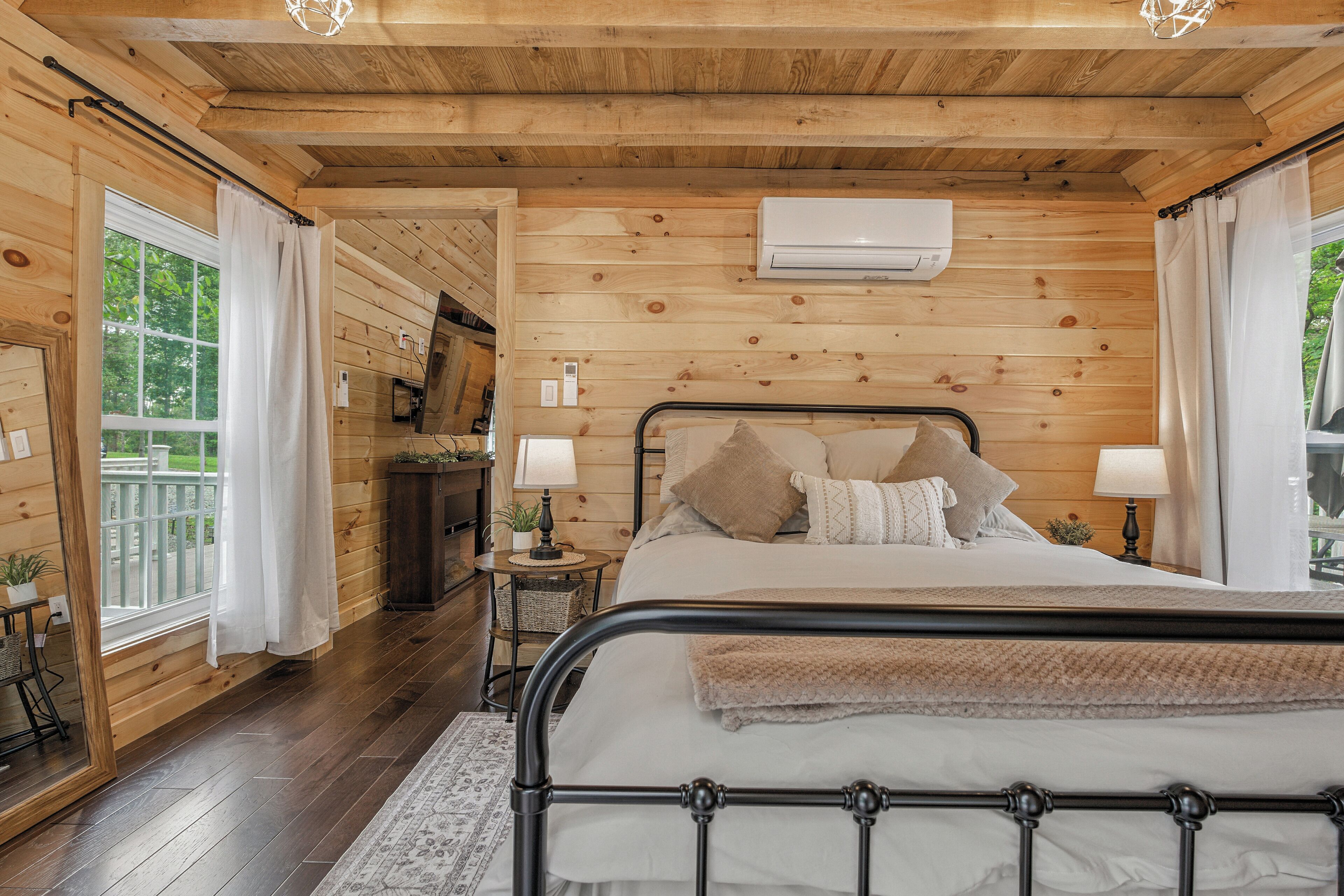 Une chambre à coucher aux murs lambrissés, avec un lit, des lampes de chevet et un appareil de climatisation.