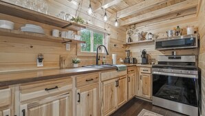 A wooden cabin-style kitchen with a built-in oven, microwave, and sink.