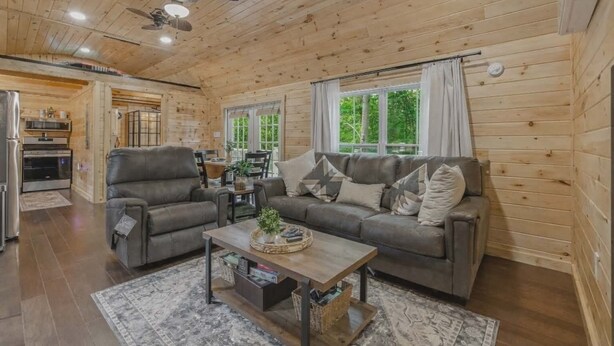 A cozy cabin-style room with a wooden interior, a sofa, a coffee table, and a dining area with a table and chairs.