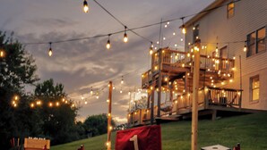 A golf course at dusk with string lights overhead and a building in the background.