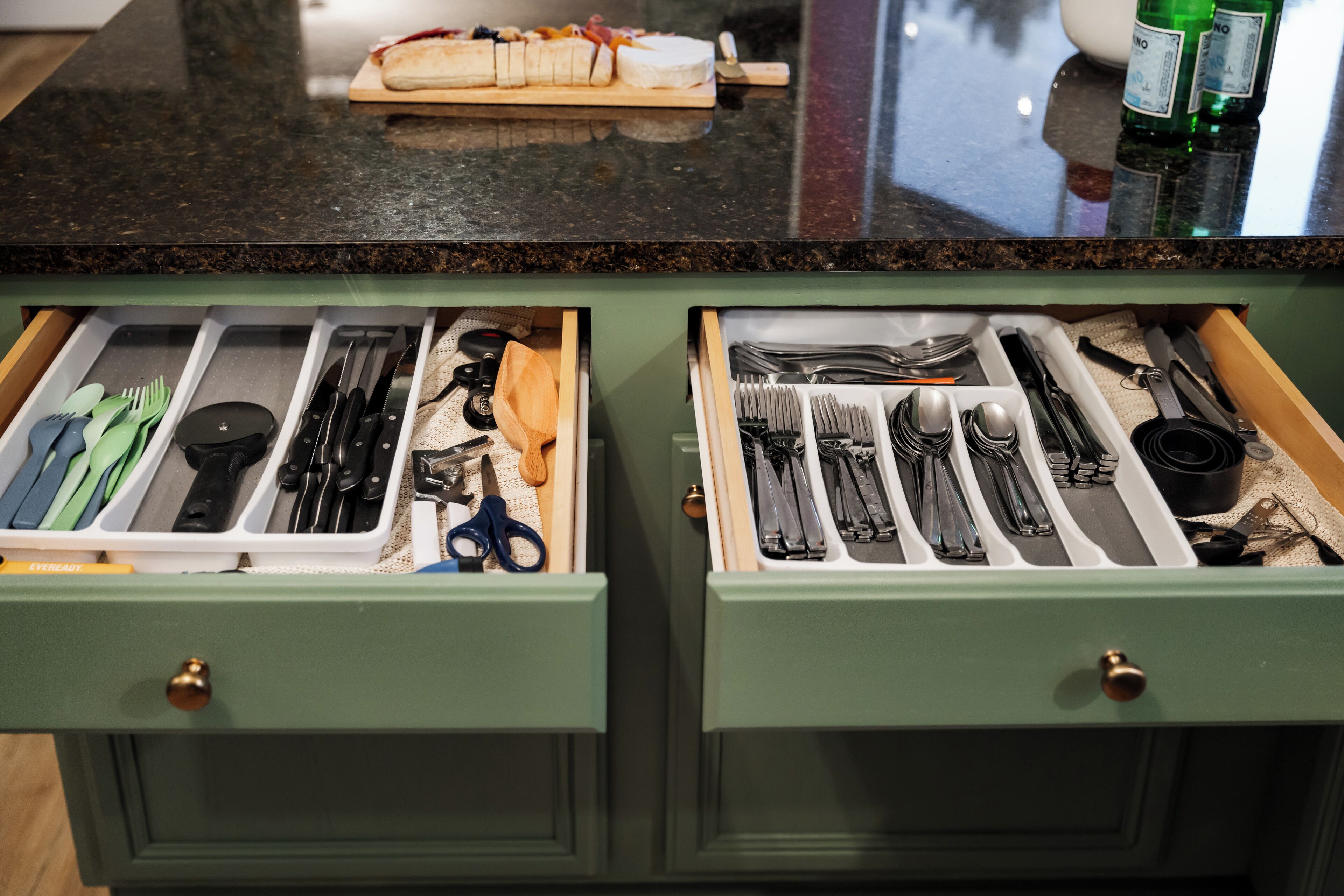 Une cuisine avec deux tiroirs ouverts contenant des ustensiles et des outils de cuisine.