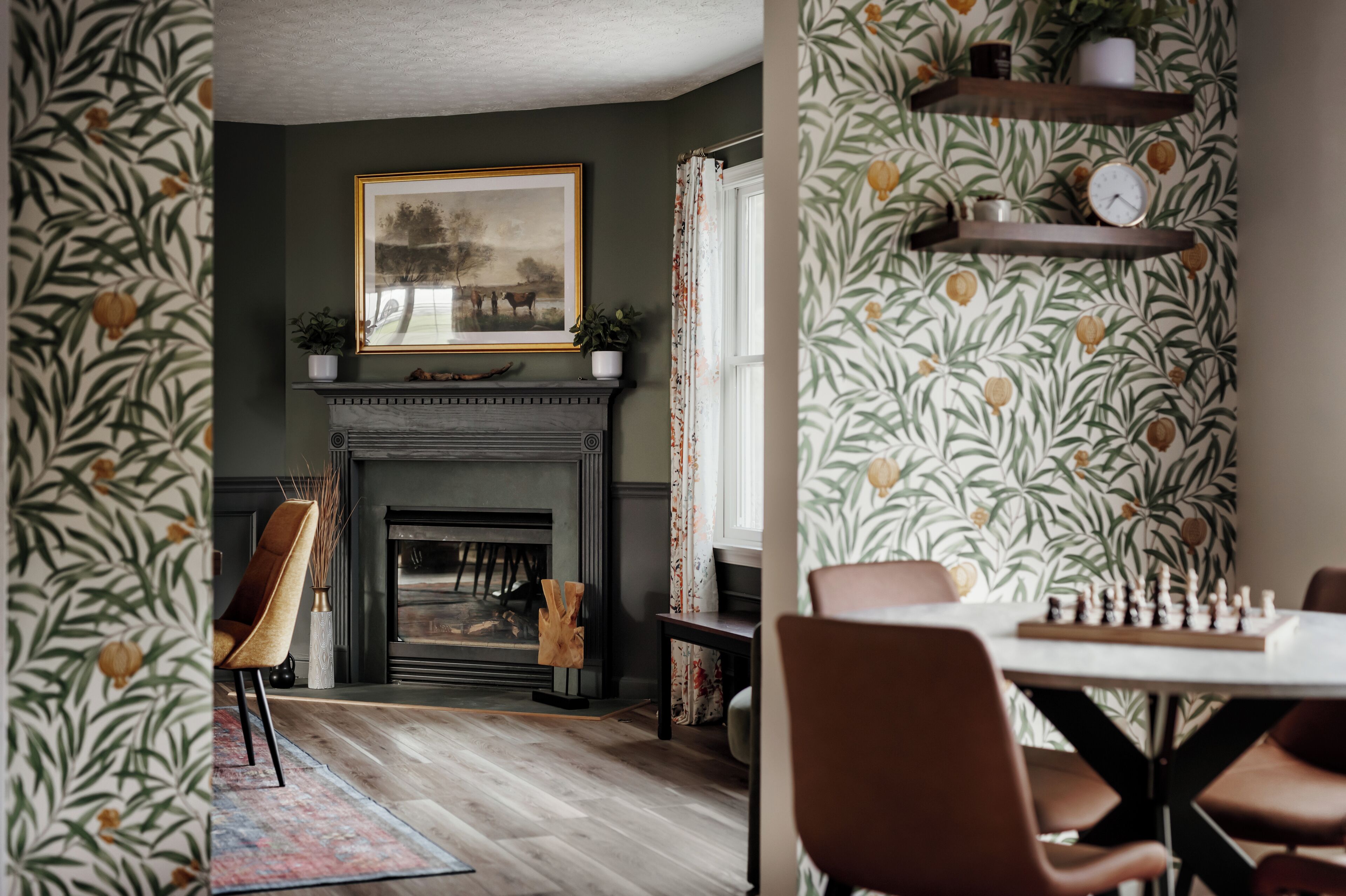 A room with a fireplace, a framed picture above it, and a chessboard on a table.