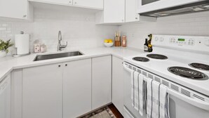 Een moderne keuken met witte kasten, een roestvrijstalen spoelbak en een inbouwoven.
