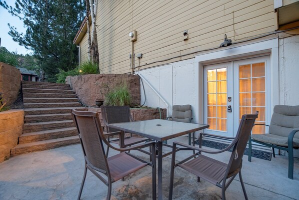 A patio with a table and chairs, a stone staircase, and a door with a window.