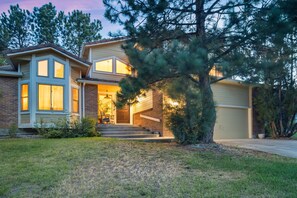 A two-story house with a front porch, a garage, and a large tree in the front yard.