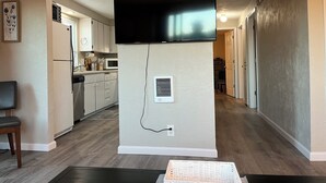 A modern kitchen with a flat-screen TV mounted on the wall, a refrigerator, and a microwave. - Charming and relaxing 2-bedroom house in quaint Springfield with AC. Sleeps 6. (Springfield)