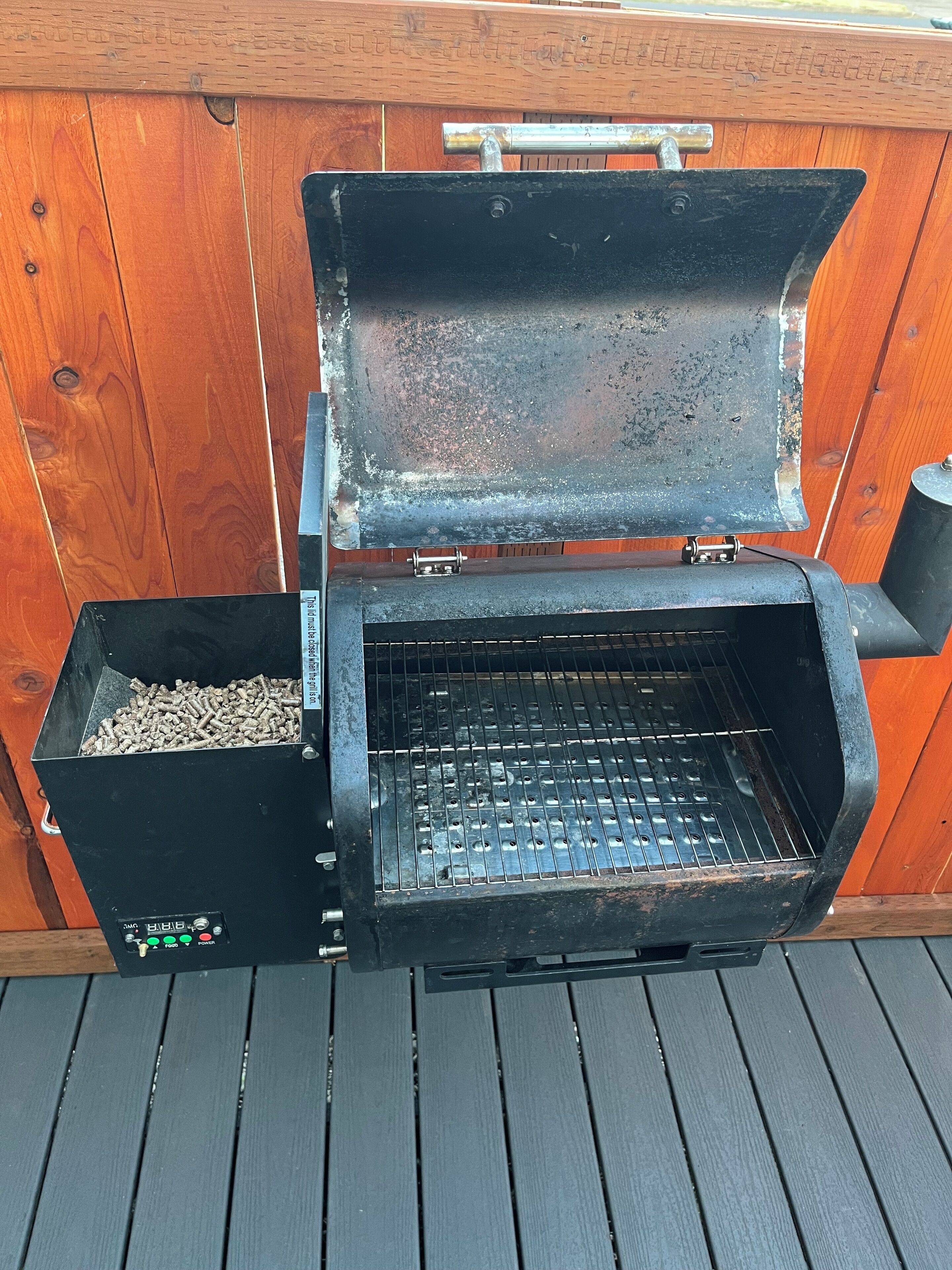 Una parrilla portátil con panel de control digital, un depósito de combustible y una rejilla de metal.