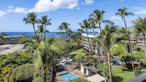 Un resort con piscina, palmeras y vista al océano.