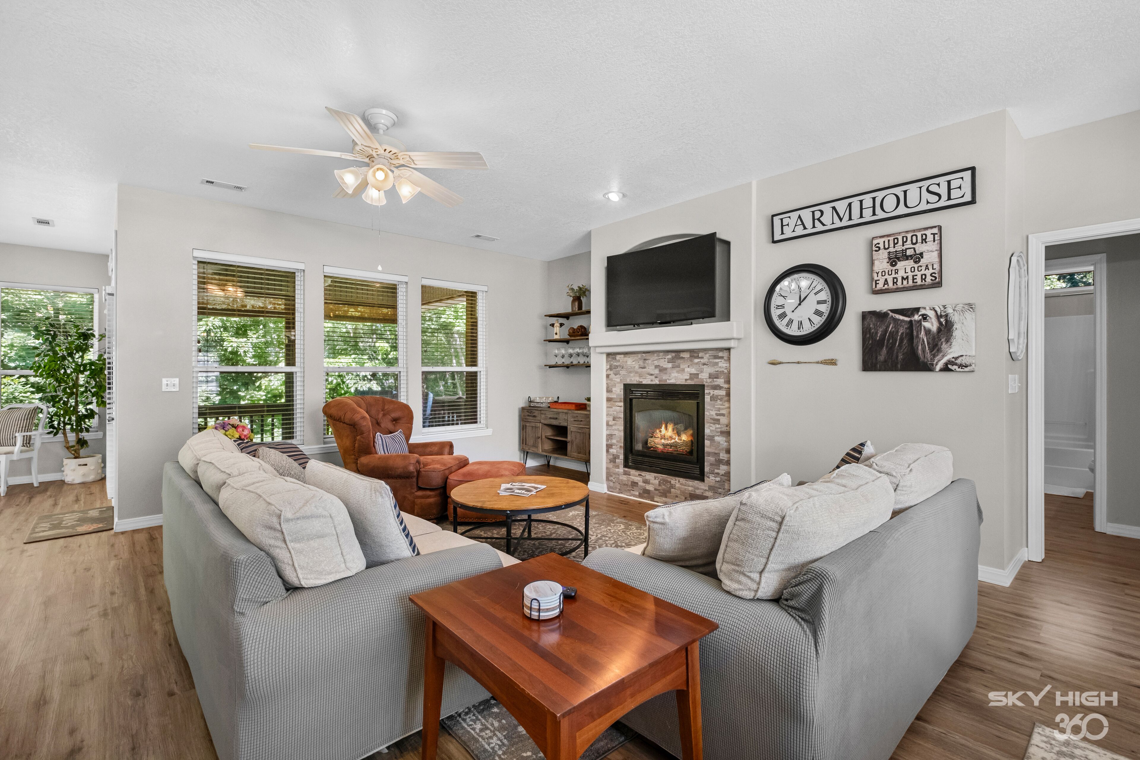 A living room with grey sofas, a wooden coffee table, a fireplace, and a TV mounted above it.