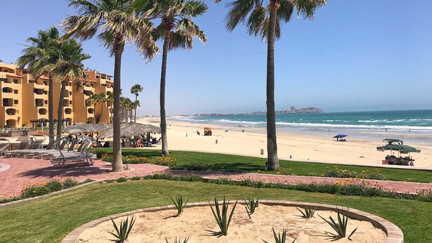 Ein Strandresort mit Palmen, einem Sandstrand und Blick aufs Meer.