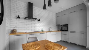 Eine moderne Küche mit weißen Schränken, einer Holz Arbeitsplatte und einer schwarzen Dunstabzugshaube.