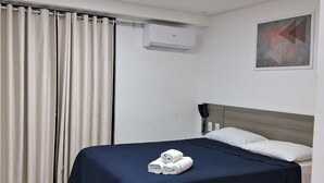 A hotel room with a bed, a curtain, an air conditioning unit, a telephone, and a painting on the wall. - Nomar II (Joao Pessoa)