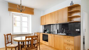 Une cuisine avec des meubles de rangement en bois, un plan de travail en marbre noir et une table à manger avec des chaises.