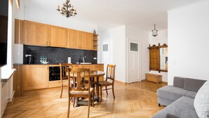Une cuisine moderne avec des meubles en bois, une table à manger avec des chaises et un canapé gris dans l’espace de vie.