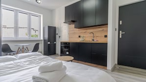 Une chambre d’hôtel moderne équipée d’un lit, d’une petite table ronde et d’une kitchenette.