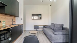 Une cuisine moderne dotée d’un four encastré, d’une table à manger et d’un canapé gris.