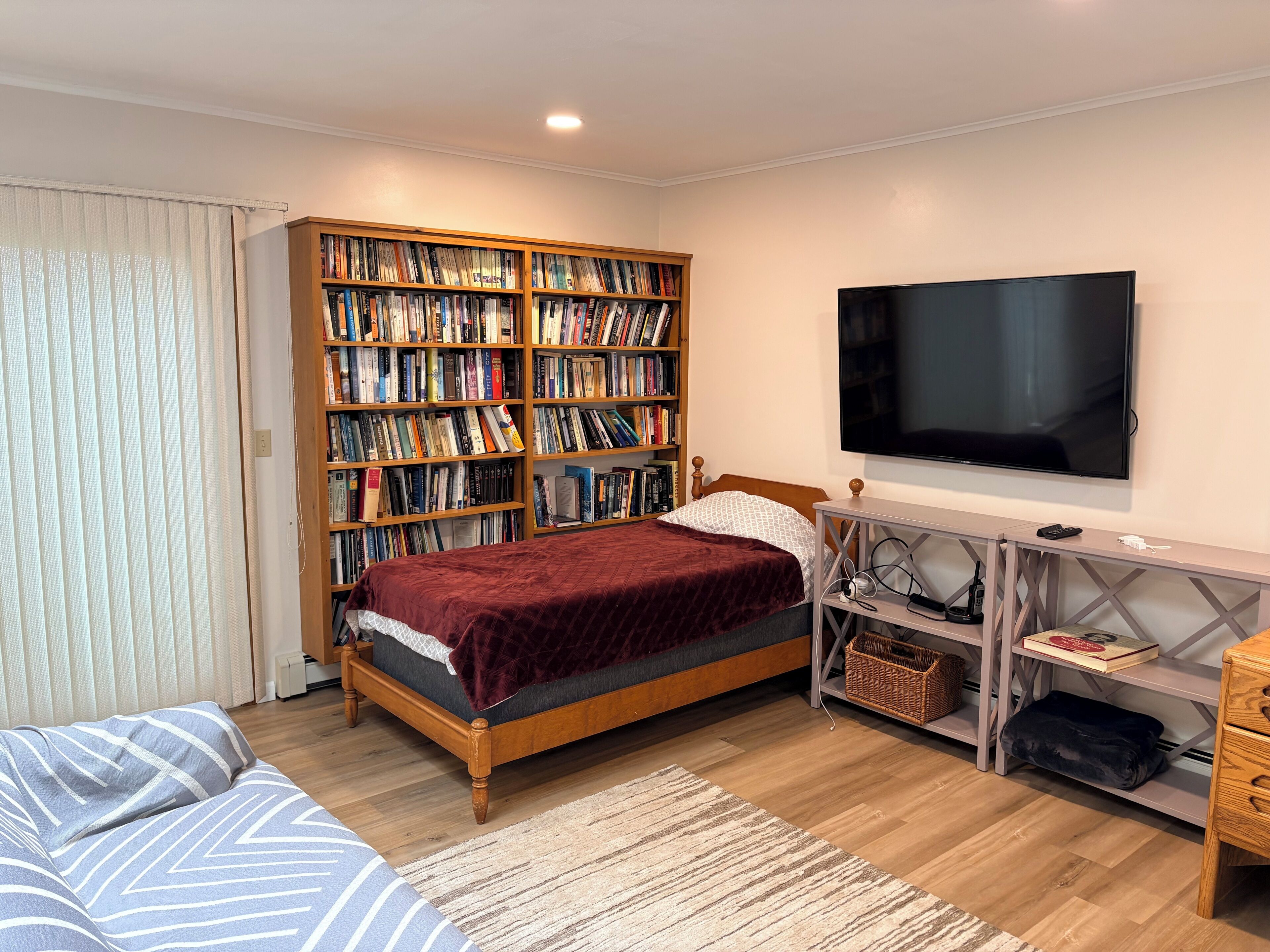 Una camera da letto con un letto, una libreria, una televisione e una scrivania.