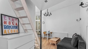 A modern living room with a sofa, a wooden coffee table, and a staircase. - Morsztynowska Studio with Mezzanine (Kraków)