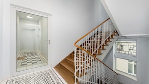 A staircase with wooden steps and white railings, leading to a landing with a window. - Morsztynowska Studio with Mezzanine (Kraków)